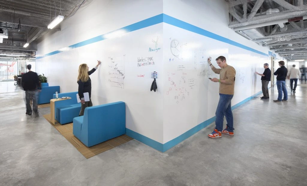 People brainstorming on whiteboard walls in a modern open-plan office