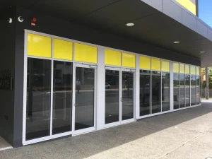 Modern shopfront with full glass windows and yellow panel highlights