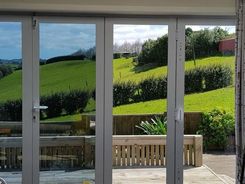 Double glass doors with countryside view of green hills and hedges