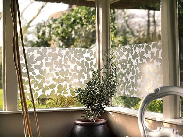 Leaf-pattern privacy film applied to sunroom windows with garden view