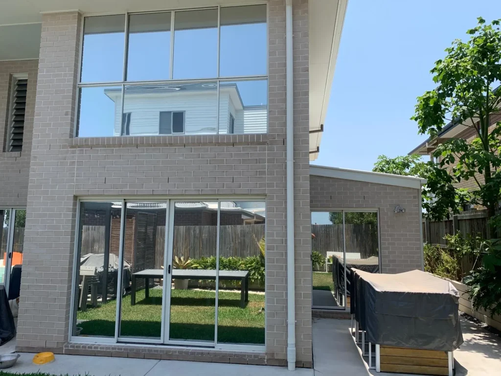 Brick home with large tinted sliding glass doors and backyard setup