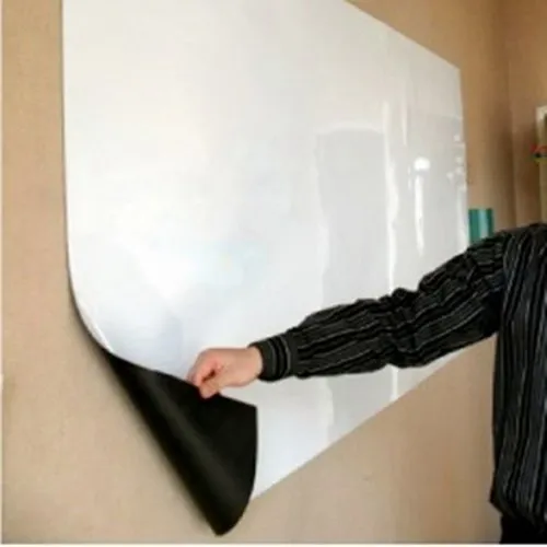 Person peeling corner of adhesive whiteboard sheet during wall install