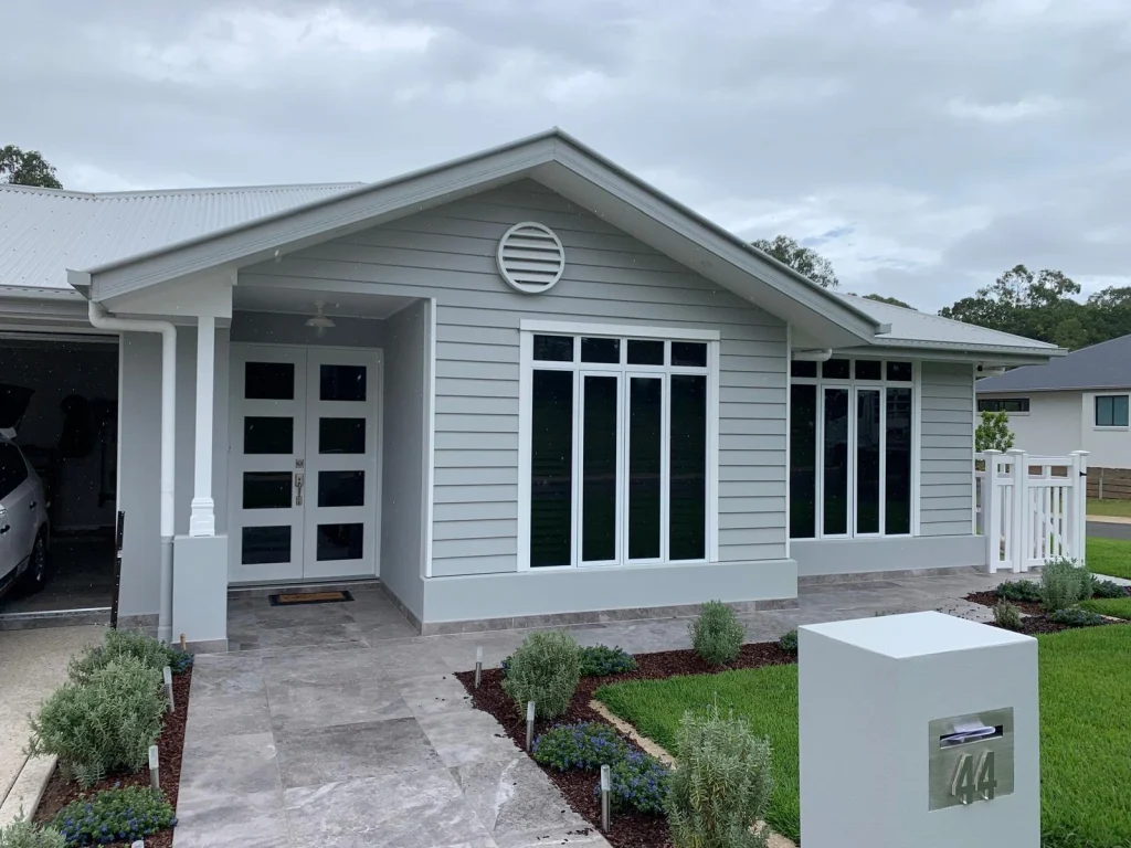 Single-storey coastal-style home with white trim and manicured garden