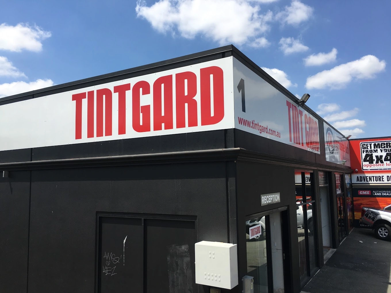 Tintgard storefront with bold red signage and clear blue sky